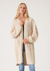 [Color: Oatmeal] A front facing image of a blonde model wearing an oatmeal chunky knit cardigan. A fall sweater with long sleeves, cable knit sleeve detail, an open front, and side pockets. 