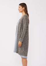 [Color: Charcoal] A side body image of a brunette model wearing a dark charcoal grey open knit cardigan sweater. A mid length lightweight cardigan with long sleeves, an open front, and ribbed wrist cuffs.