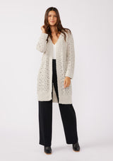 [Color: Oatmeal] A full body front facing image of a brunette model wearing an oatmeal open knit cardigan sweater. A mid length lightweight cardigan with long sleeves, an open front, and ribbed wrist cuffs.