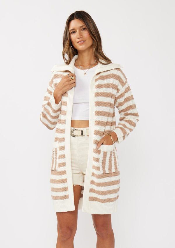 [Color: Natural/Taupe] A front facing image of a brunette model wearing a mid length cardigan in a natural and taupe stripe. With long sleeves, a collared neckline, an open front, and side pockets.