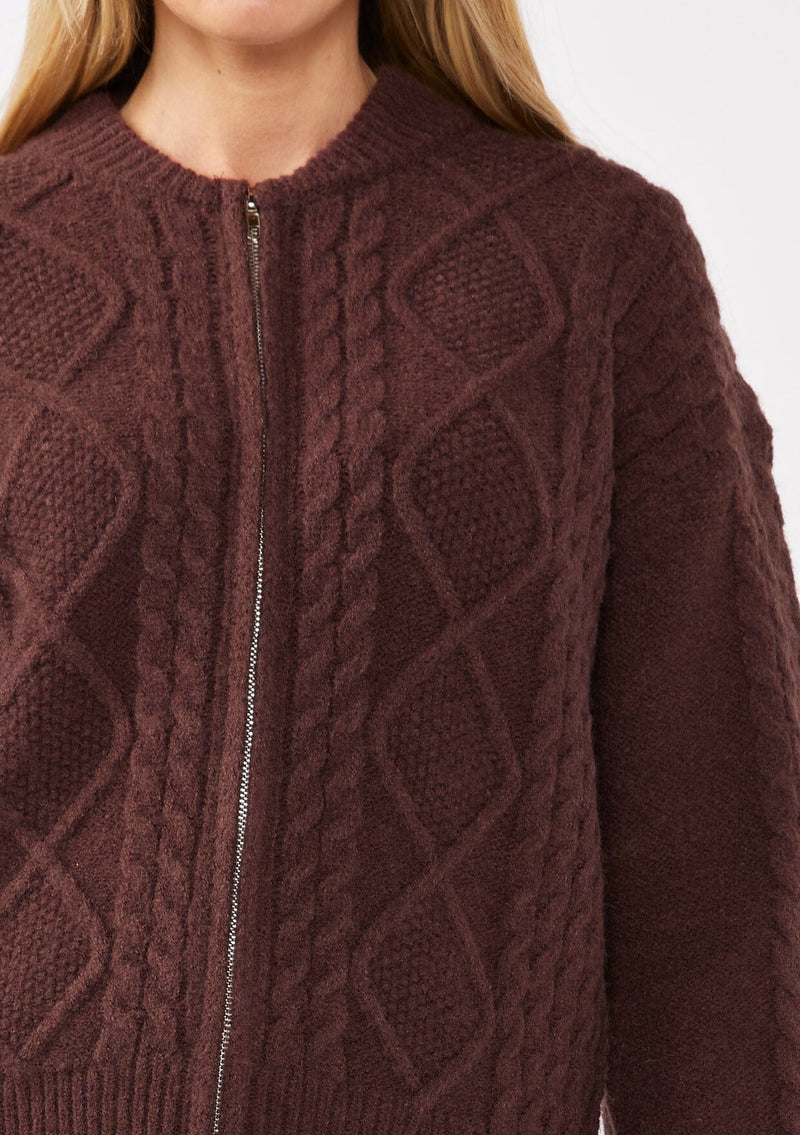 [Color: Dark Brown] A blonde model wearing an brown cozy knit sweater with a zipper front. Featuring long sleeves and classic ribbed trims. A versatile sweater perfect for layering and styling any fall ensemble. 