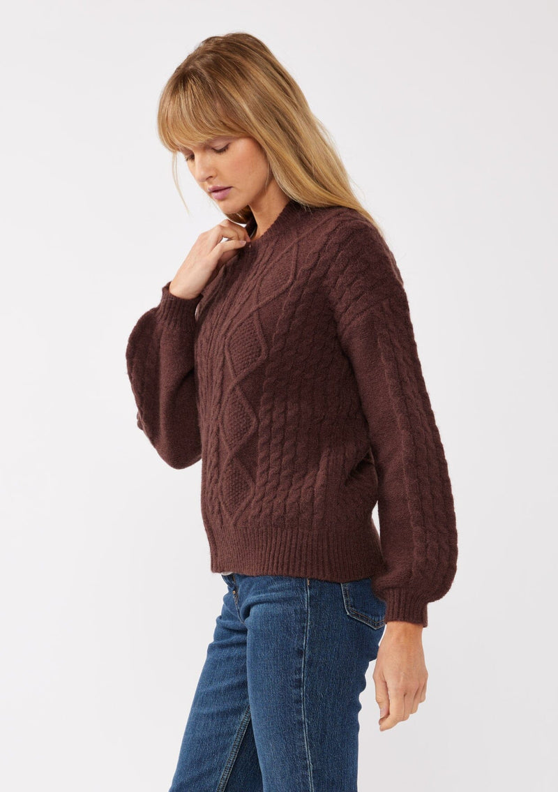 [Color: Dark Brown] A blonde model wearing an brown cozy knit sweater with a zipper front. Featuring long sleeves and classic ribbed trims. A versatile sweater perfect for layering and styling any fall ensemble. 