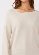 [Color: Heather Stone] A brunette model wearing a beige off white relaxed fit sweater with an asymmetrical neckline and long sleeves with a dropped shoulder. An everyday pullover sweater styled with dark denim jeans for the fall season.