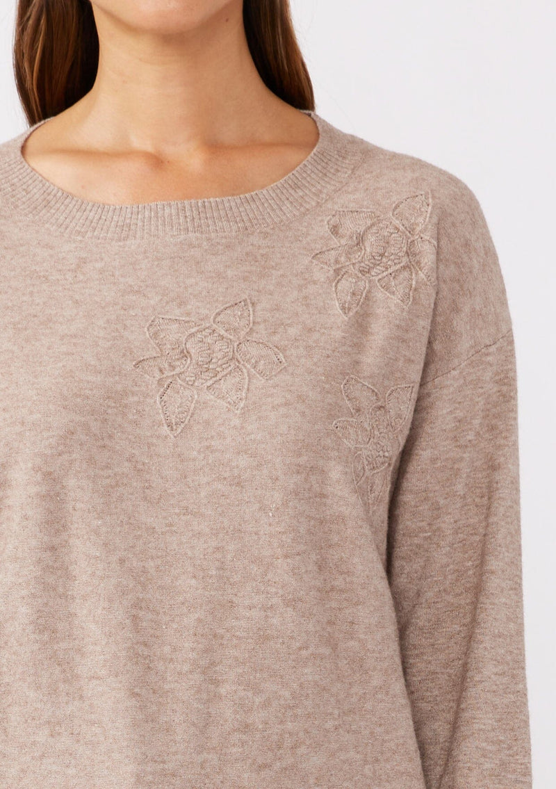 [Color: Heather Mocha] A detail  image of a brunette model wearing a casual light brown pullover sweater with tonal embroidery. This lightweight fall sweater features long sleeves, a classic round neckline, and rib trimming. 