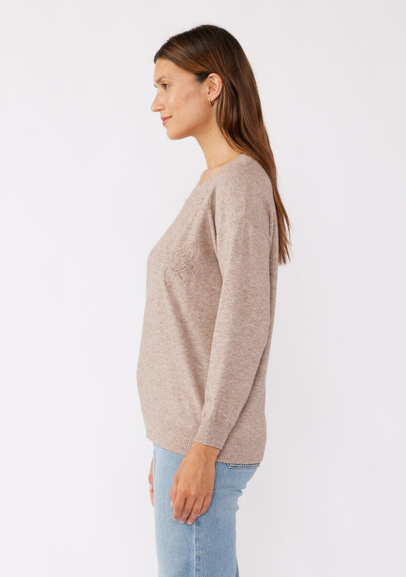 [Color: Heather Mocha] A side facing image of a brunette model wearing a casual light brown pullover sweater with tonal embroidery. This lightweight fall sweater features long sleeves, a classic round neckline, and rib trimming. 