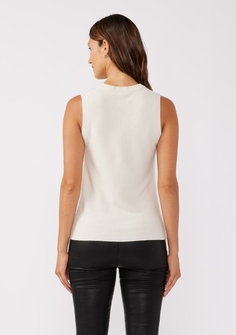 [Color: Vanilla] A back facing image of a brunette model wearing a cozy off white sweater tank top with a ribbed texture, twisted front hemline and a round neckline. A relaxed casual top for the spring season. 