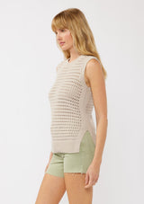 [Color: Mushroom] A side facing image of a blonde model wearing a sleeveless open knit sweater vest with a crew neckline, ribbed trim, and side slits. Perfect for layering over long sleeves or wearing on its own. 