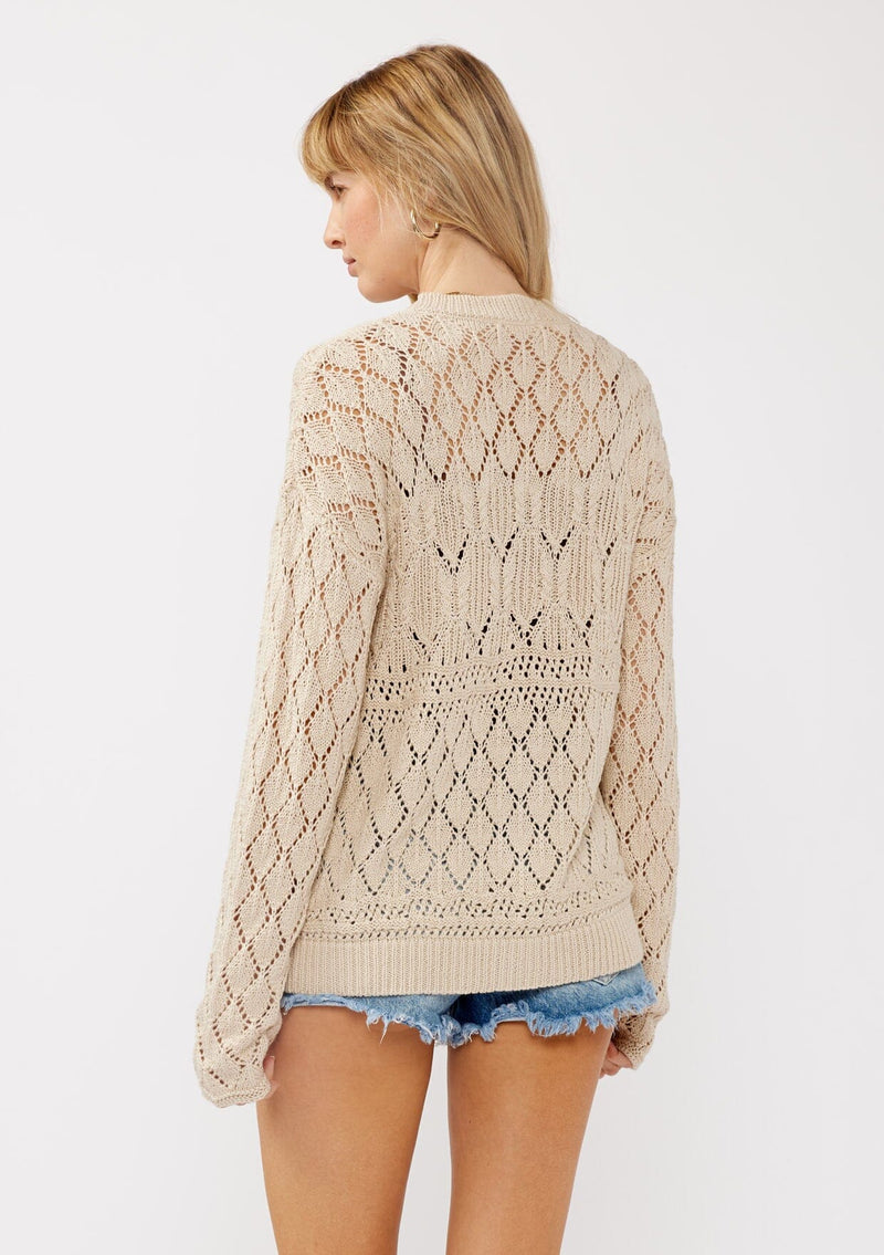 [Color: Vanilla] A back facing image of a blonde model wearing wearing a light 
beige pointelle cardigan with an open knit design, button front, v-neckline, long sleeves, and ribbed trim, ideal for versatile spring layering.