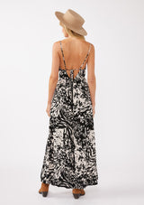 [Color: Black/Blush] A back facing image of a blonde model wearing a black and ivory abstract print maxi dress. This spaghetti strap maxi features a flattering v-neckline, front slits, and a strappy back. This classic bohemian style is perfect for year-round versatility.