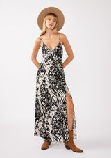 [Color: Black/Blush] A front facing image of a blonde model wearing a black and ivory abstract print maxi dress. This spaghetti strap maxi features a flattering v-neckline, front slits, and a strappy back. This classic bohemian style is perfect for year-round versatility.