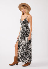 [Color: Black/Blush] A side facing image of a blonde model wearing a black and ivory abstract print maxi dress. This spaghetti strap maxi features a flattering v-neckline, front slits, and a strappy back. This classic bohemian style is perfect for year-round versatility.