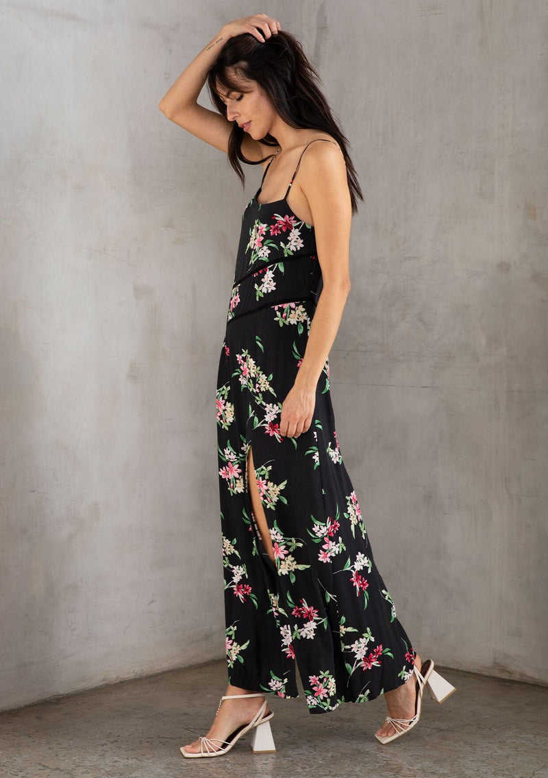 [Color: Black/Red] A brunette model wearing a black dress with a red floral design. A slit maxi dress with a scoop neckline, adjustable spaghetti straps, and lattice trims. A versatile dress for day to night.