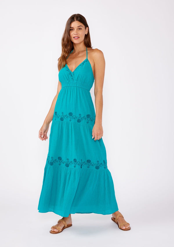[Color: Teal Blue] A brunette model wearing a  teal bohemian maxi dress. A classic halter maxi dress with a v neck, smocked empire waist, tiered skirt, and floral embroidered details.  