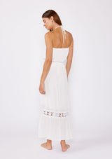 [Color: Off White] A brunette model wearing a white ultra bohemian maxi dress for vacation. This summer maxi dress features a halter neckline and a comfortable smocked waist. This dress is also embellished with intricate lace details and embroidered eyelet. The perfect style for brunch or a tropical vacation. 