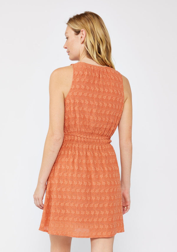 [Color: Terracota] A blonde model wearing a fall burnt orange mini dress with a delicate embroidered floral through out. With a sleeveless design, surplice v neckline, and a double elastic waistline. A casual mini dress that can be worn to a brunch or special wedding occasions.