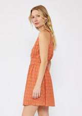 [Color: Terracota] A blonde model wearing a fall burnt orange mini dress with a delicate embroidered floral through out. With a sleeveless design, surplice v neckline, and a double elastic waistline. A casual mini dress that can be worn to a brunch or special wedding occasions.