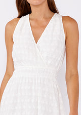 [Color: White] A brunette model wearing a white mini dress with a delicate embroidered floral through out. With a sleeveless design, surplice v neckline, and a double elastic waistline. A casual mini dress that can be worn to a brunch or special wedding occasions.