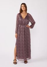 [Color: Black/Plum] A full body image of a brunette model wearing a black and purple floral print maxi dress with shimmering metallic details. This holiday dress features long sleeves, a split v neckline with ties, an elastic waistline, and side slits. Perfect for festive gatherings and formal events. 