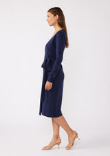 [Color: Navy] A brunette model wearing a sweater midi wrap dress in navy blue. Featuring a flattering v neckline, side tie closure, and long sleeves. A versatile cozy knit dress for the office or special occasions.  