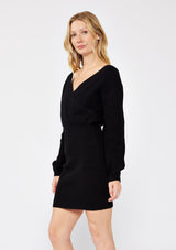 [Color: Black] A blonde wearing a cozy knit dress in black. A fitted sweater dress with a surplice v neckline, long sleeves, and a stretchy knit  in cotton blend. Perfect for the fall season and colder temperatures. 