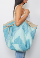 [Color: Natural/Blue/Sky] A reversible bohemian tote bag with double top handles, oversized grommets, an attached pouch with zip closure, and a tie closure. 