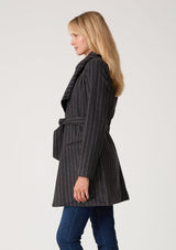 [Color: Charcoal] A blonde model wearing a dark grey pinstripe relaxed-fit, mid-length belted coat with an oversized shawl collar and side pockets. 