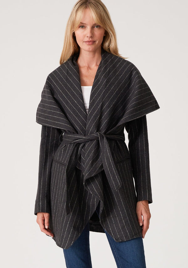 [Color: Charcoal] A blonde model wearing a dark grey pinstripe relaxed-fit, mid-length belted coat with an oversized shawl collar and side pockets. 