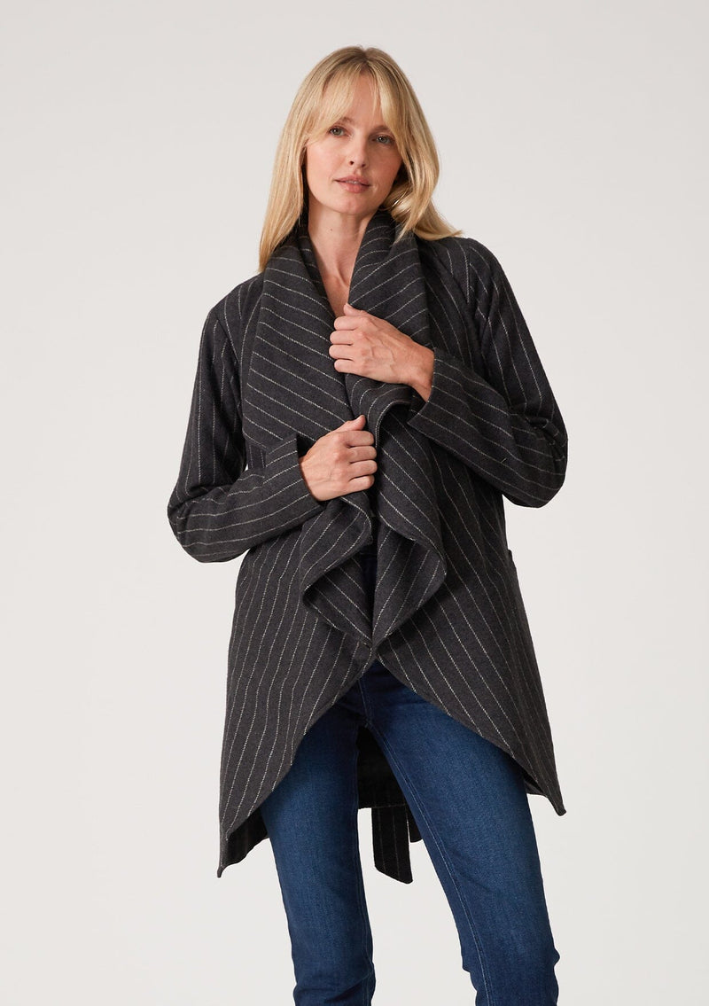 [Color: Charcoal] A blonde model wearing a dark grey pinstripe relaxed-fit, mid-length belted coat with an oversized shawl collar and side pockets. 