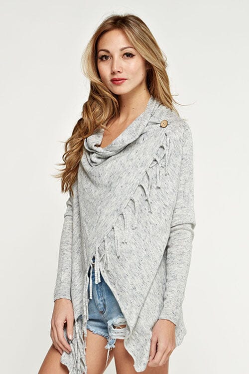 [Color: Blue/Vanilla] A blonde model wearing a blue and ivory speckled cardigan with a wrap front. Featuring a fringed hem, long sleeves, and a relaxed fit. 