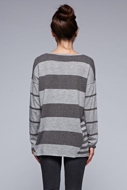 [Color: Charcoal/Heather Grey] A back facing image of a brunette model wearing a grey patchwork striped knit pullover with a v-neckline, long sleeves, dropped shoulders, and exposed seams. 