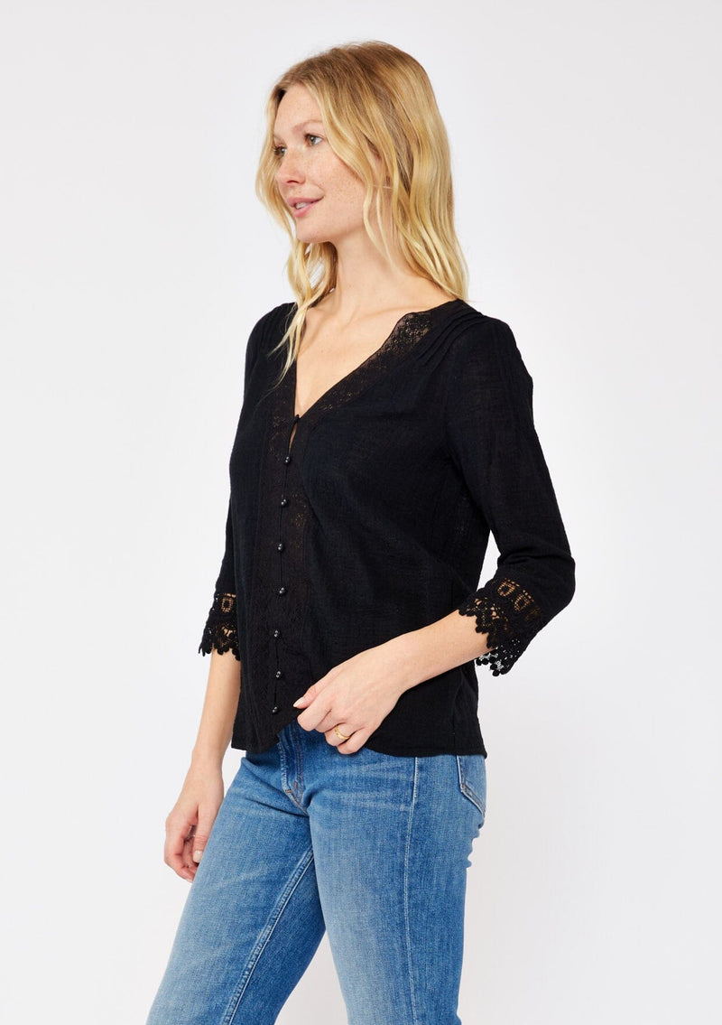 [Color: Black] A blonde model wearing a textured cotton blouse in black. With lace and crochet trims, functional button front, v neckline, and relaxed fit. A casual bohemian top paired with denim jeans.