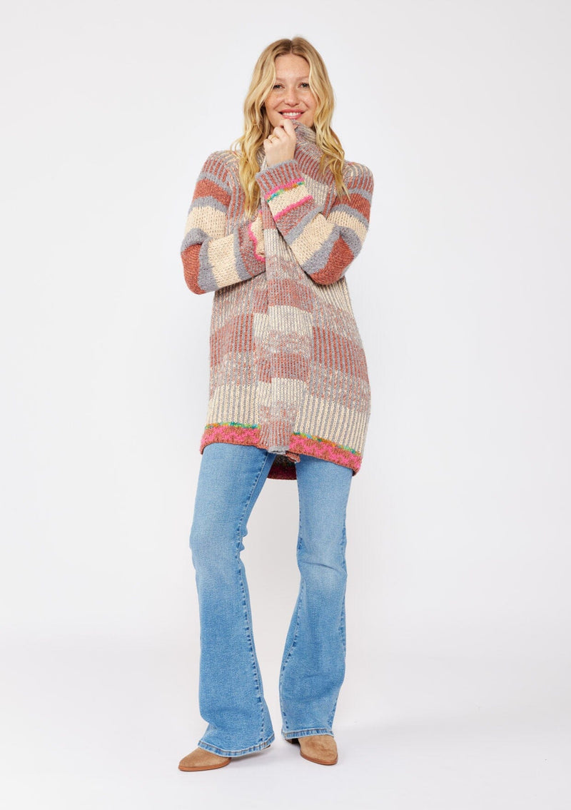 [Color: Natural/Dusty Clay] A blonde model wearing an ultra soft cardigan in a multicolor heather stripe knit. Featuring an open front, relaxed shawl collar, and cozy long sleeves. Paired and styled with vintage denim and boots for the ultimate fall look.