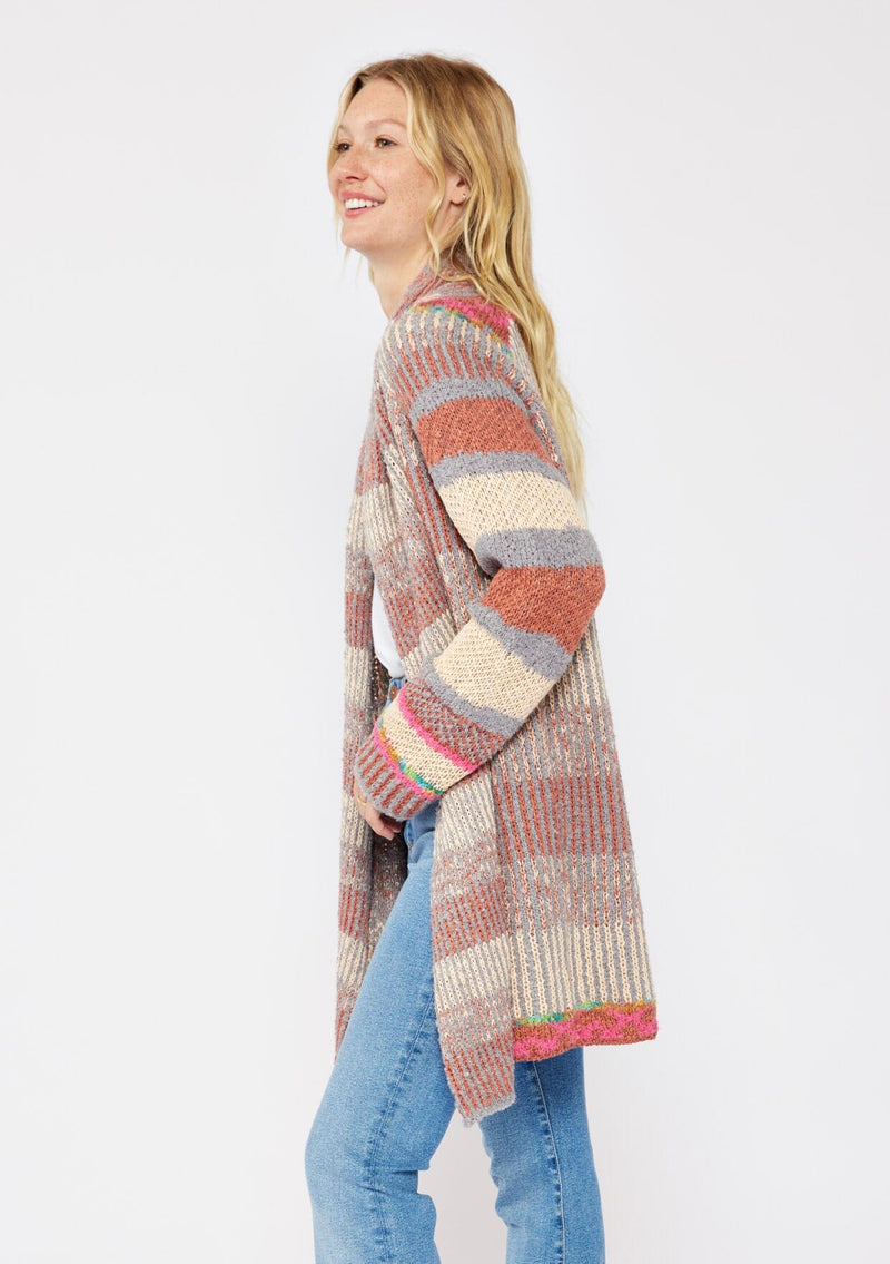 [Color: Natural/Dusty Clay] A blonde model wearing an ultra soft cardigan in a multicolor heather stripe knit. Featuring an open front, relaxed shawl collar, and cozy long sleeves. Paired and styled with vintage denim and boots for the ultimate fall look.