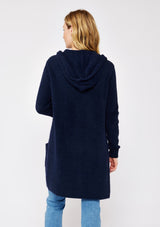 [Color: Navy] A navy blue cardigan with a fuzzy texture and soft touch. Features a hood, long sleeves, and patch pockets. A versatile cardigan layered with a white top for easy styling. Paired and styled with vintage denim and boots for the ultimate cozy look.