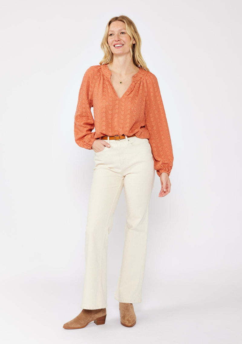 [Color: Terracota] A blonde model wearing a pretty floral embroidered top with eyelet details. A breezy Fall top with a ruffled split v neckline and long sleeves with an elastic cuff. An everyday burnt orange styled with casual light beige pants.