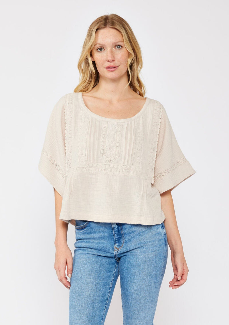 [Color: Natural] A blonde model wearing a soft cotton gauze top in beige natural. With a scoop neckline, embroidered front detail, and kimono sleeves. A relaxed fit top for lounging  or a casual day out. Paired with denim jeans for a laid back style. 