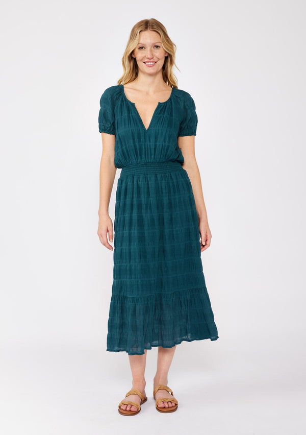 [Color: Deep Teal] A blonde model wearing a teal midi dress with a subtle woven striped design. With a split v-neckline, short puff sleeves, smocked waistline, and a ruffle trimmed hem. 