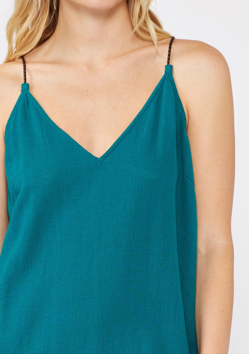 [Color: Forest Teal] A blonde model wearing a flowy, casual summer dress in a teal solid print. With a v neckline, relaxed fit, and faux braided leather straps that are adjustable at the back. A cute back slit dress for the summer season, perfect for vacation or beachside stroll. Classic cotton dress. 