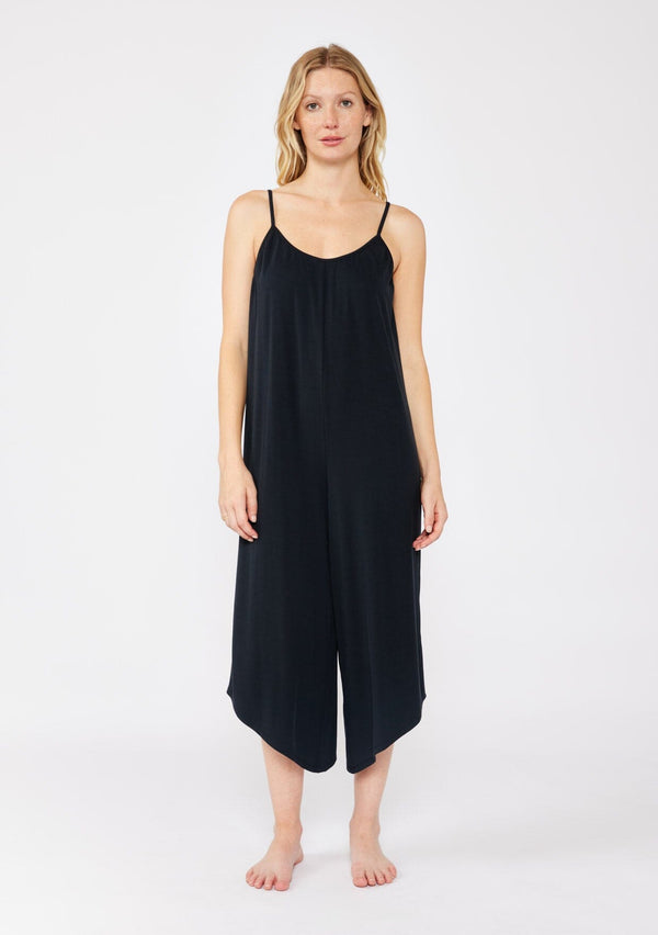 [Color: Black] A blonde model wearing an ultra soft knit jumpsuit with a cropped leg. A sleeveless black jumpsuit with a scoop neckline and adjustable spaghetti straps. A lounge jumpsuit designed with an oversized fit and stretchy fabric. 