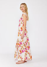 [Color: Natural/Orchid] A blonde model wearing a large floral print maxi dress in orange and pink florals. With a square neckline, tie front neckline detail, smocked back, flutter cap sleeves, and a side slit. A fall maxi dress paired with strappy sandals.