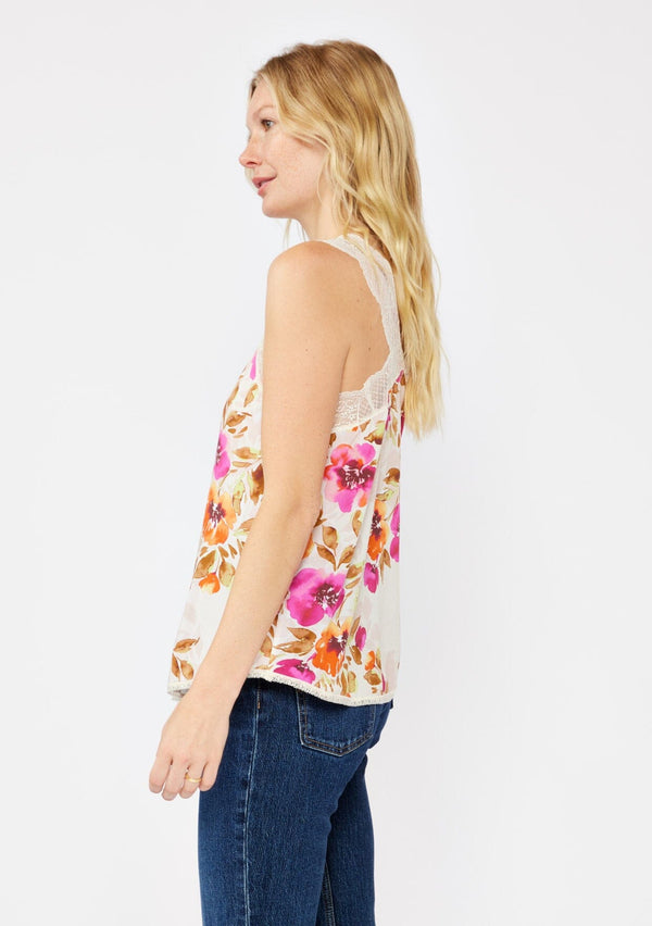 [Color: Natural/Orchid] A blonde model wearing a pretty lace trim cami tank top. A floral print tank with a v neckline, racerback, and relaxed fit. Styled with dark denim jeans for the perfect fall look.