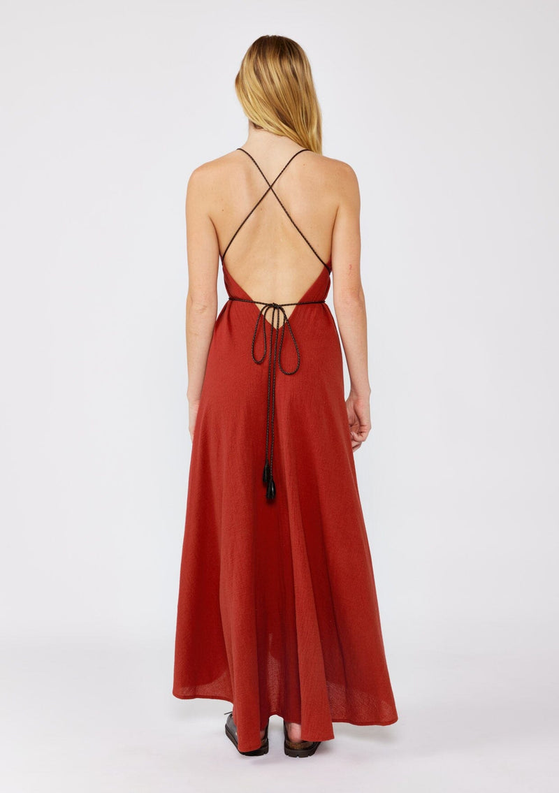 [Color: Sienna] A blonde model wearing an ultra bohemian Fall maxi dress with slip on chunky sandals. A cotton maxi dress in a red wine solid print, ruched v neckline, adjustable braided straps, open cross back, and relaxed fit. A casual cotton maxi for a dreamy summer to fall transition.