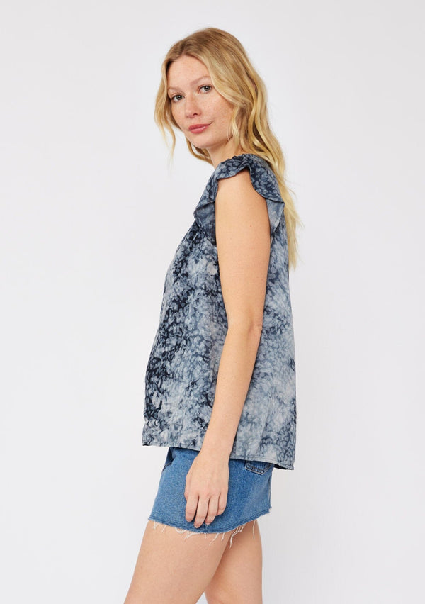 [Color: Indigo] A blonde model wearing a blue animal print top with a denim mini skirt. A relaxed fit top with a split v neckline and short flutter sleeves.