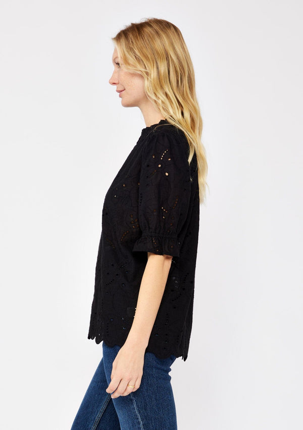 [Color: Black] A blonde model wearing a black top with a high round neckline, button front, and puff sleeves. Features a ruffled elastic cuff for added flair. A summer top with no lining for a comfortable breezy fit for the summer.