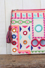 [Color: Pink Multi] An image of a multi color embroidered clutch with light reflecting details and a tassel zipper pull. 