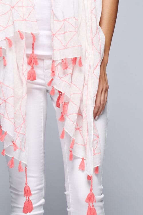 [Color: Pink] A brunette model wearing a lightweight cotton scarf with contrast embroidery and a vibrant tassel trim, adding a stylish touch to her all white look. 