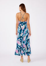 [Color: Teal/Dusty Orchid] A brunette model wearing a beautiful tropical print maxi dress with wedges. A tiered maxi dress with ruffle trim details, spaghetti straps, cross back, and v neckline. A vacation style dress with an empire waistline for a flowy fit.