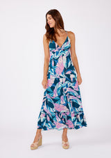 [Color: Teal/Dusty Orchid] A brunette model wearing a beautiful tropical print maxi dress with wedges. A tiered maxi dress with ruffle trim details, spaghetti straps, cross back, and v neckline. A vacation style dress with an empire waistline for a flowy fit.