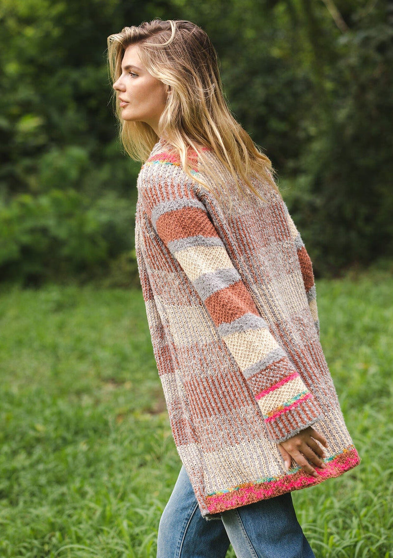 [Color: Natural/Dusty Clay] A blonde model wearing an ultra soft cardigan in a multicolor heather stripe knit. Featuring an open front, relaxed shawl collar, and cozy long sleeves. Paired and styled with vintage denim.