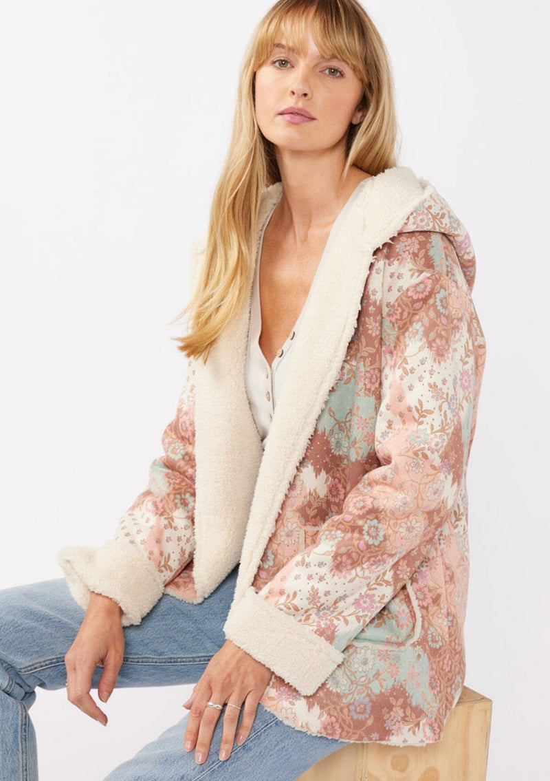 [Color: Brick/Cream] A blonde model wearing a popular floral jacket with sherpa lining. This cozy fall and winter jacket features long sleeves, patch pockets, and a hoodie, draped for all-day comfort and warmth. Ideal for colder temperatures.